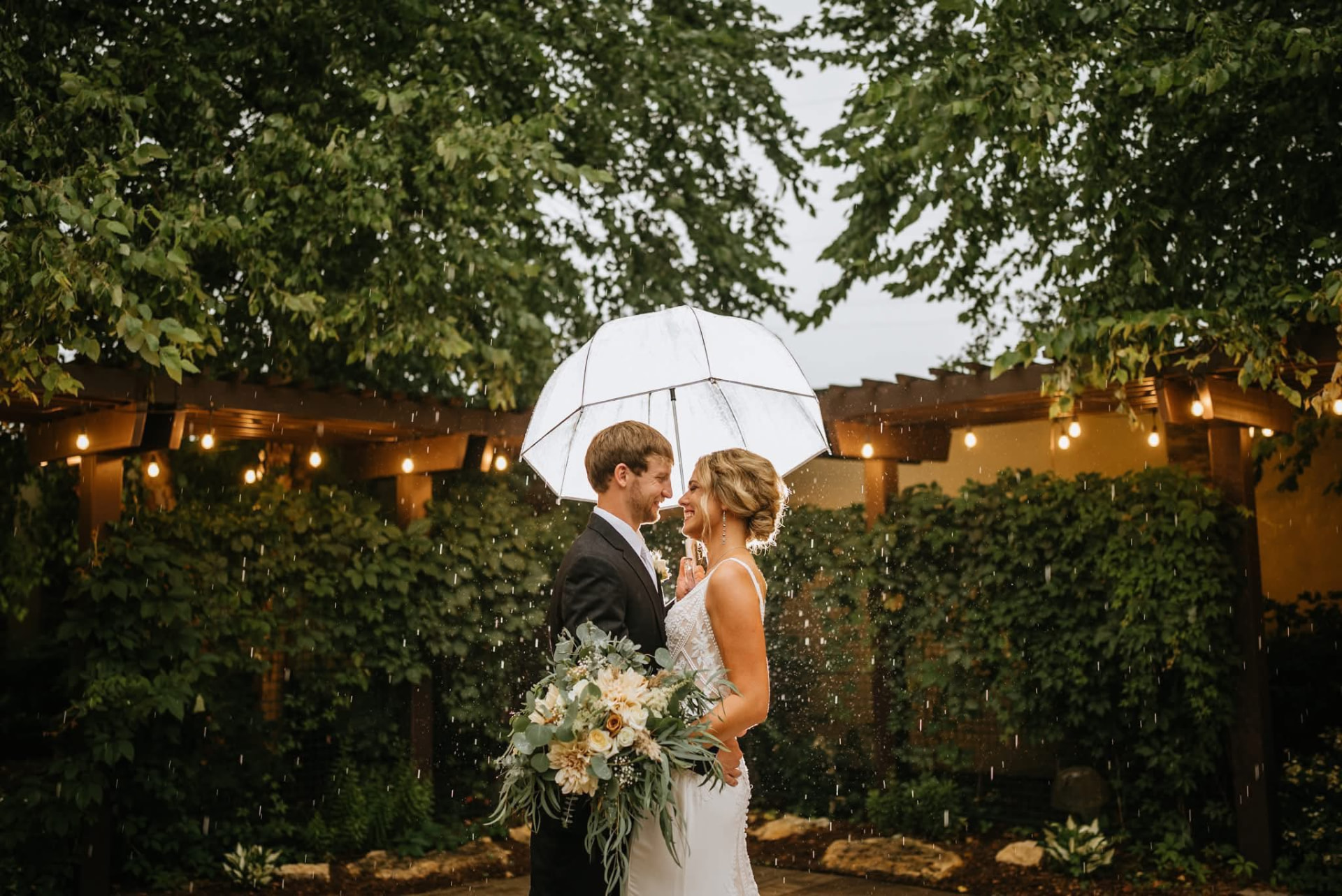 Newlywed couple under an umbrella in the landscaped courtyard at Courtyard by Marriott Mankato